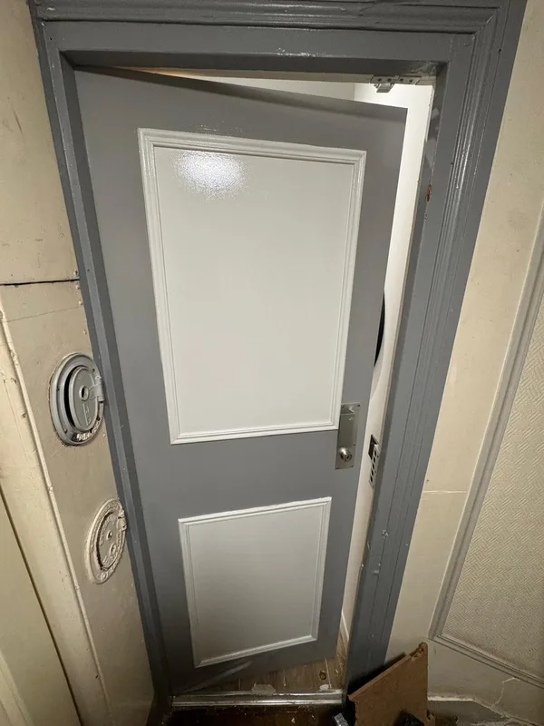Porte palière grise avec serrure posée dans immeuble ancien