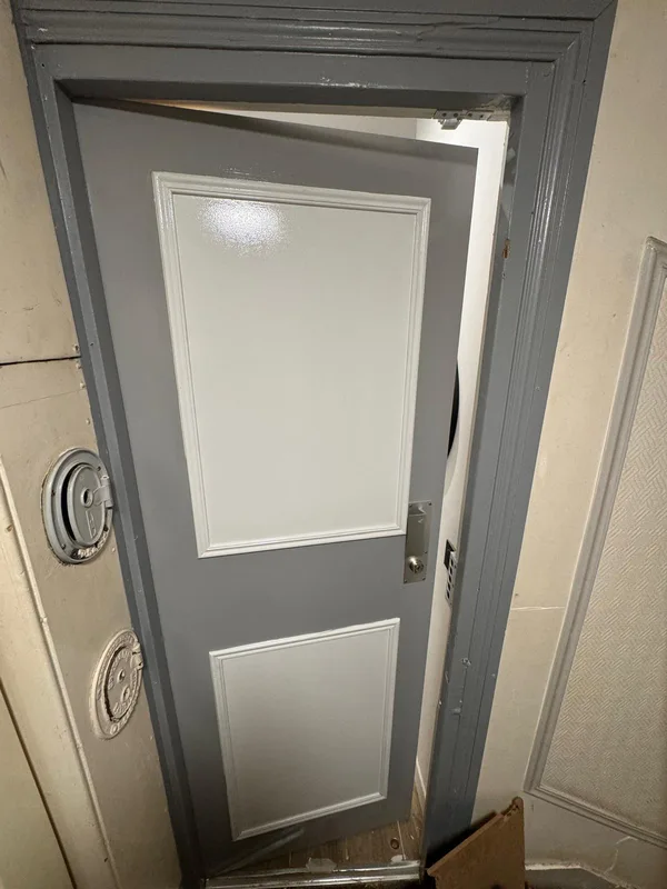 Porte palière grise avec serrure posée dans immeuble ancien